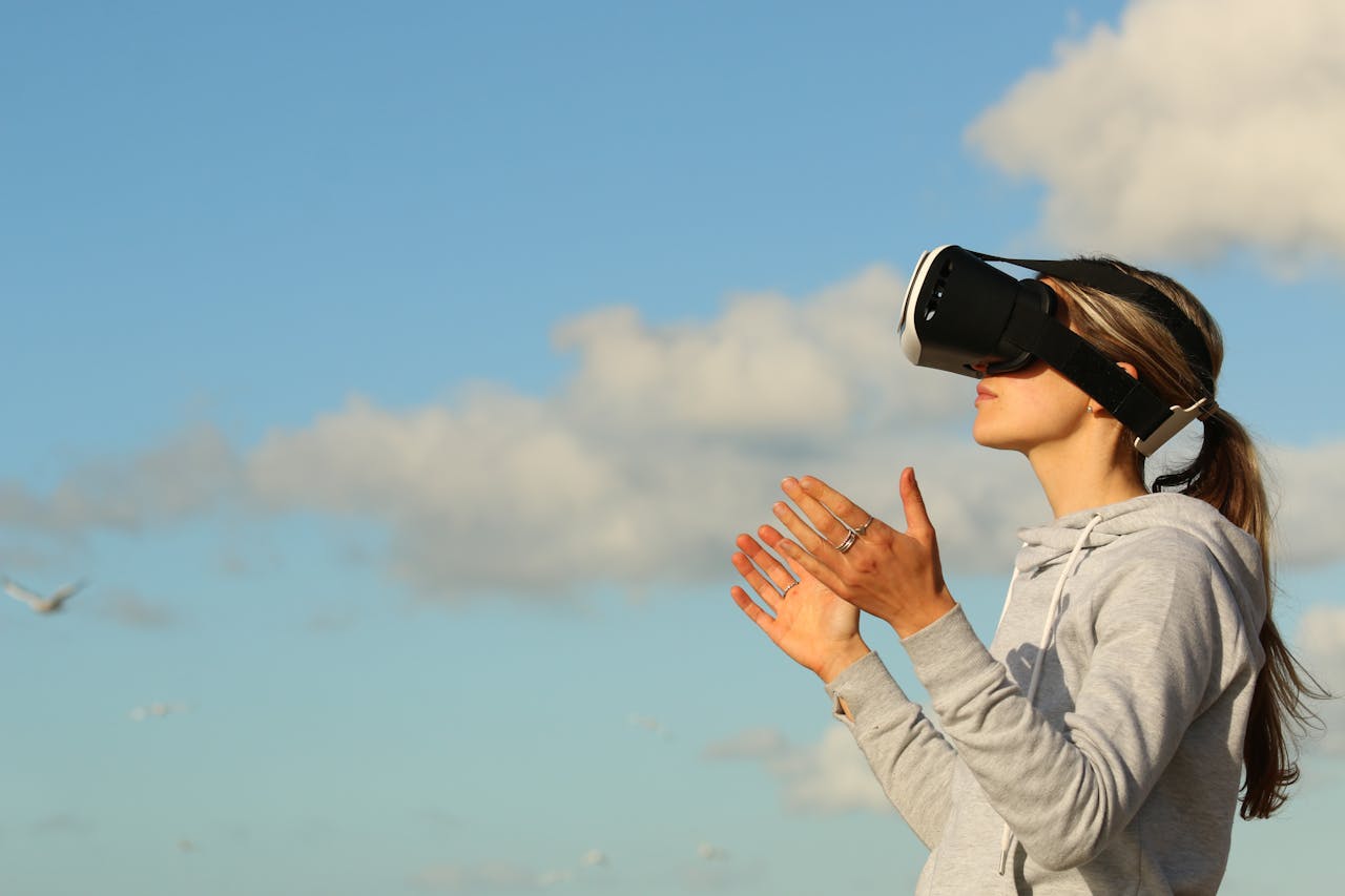 heros-img Woman using VR headset outdoors, exploring virtual reality under a clear blue sky.