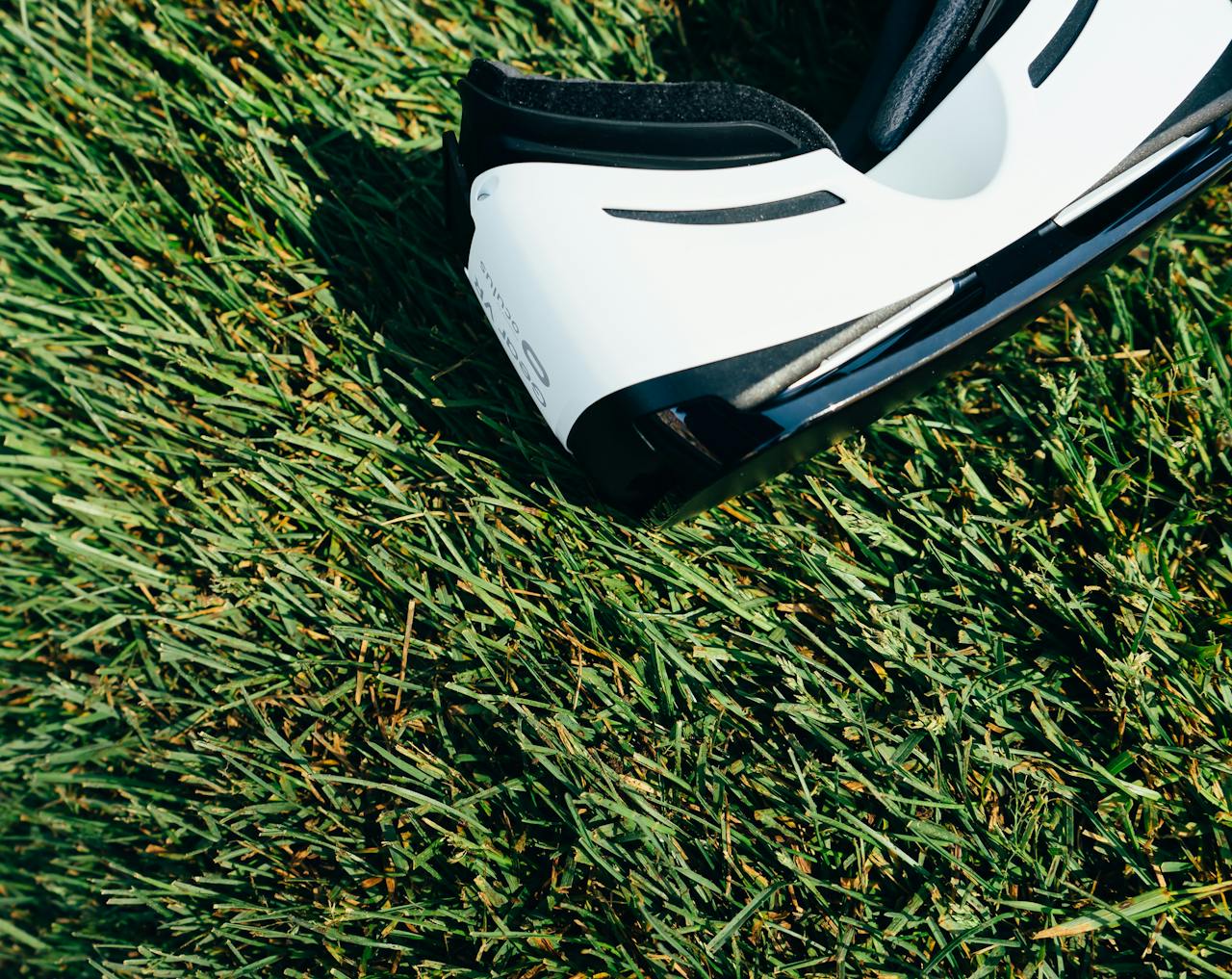 about-us-01 A close-up shot of VR goggles placed on a green grass lawn under sunlight.